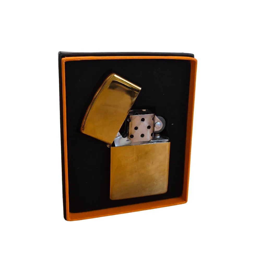 Gold flip-top lighter with metallic accents in a black box on a white background