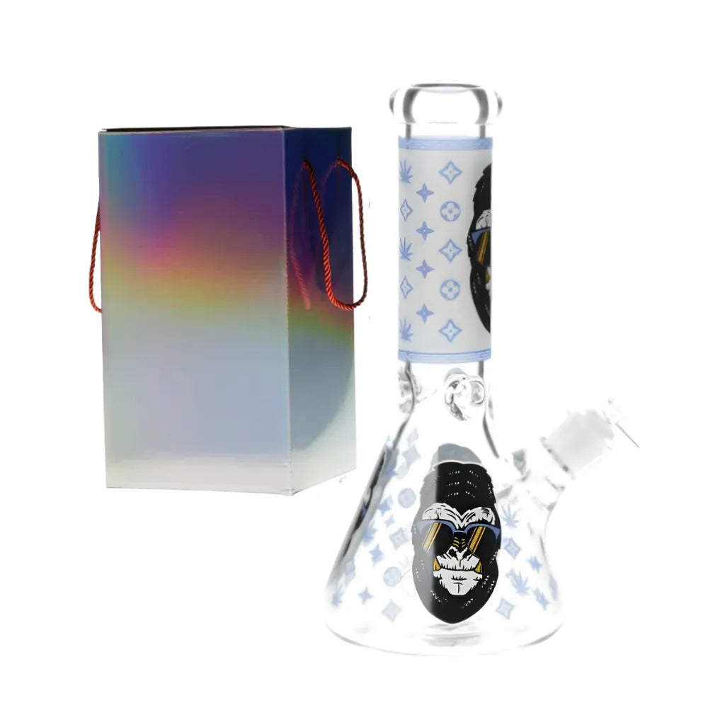 Glass glow in the dark bong with a gorilla design with blue accents with colourful packaging on a white background.