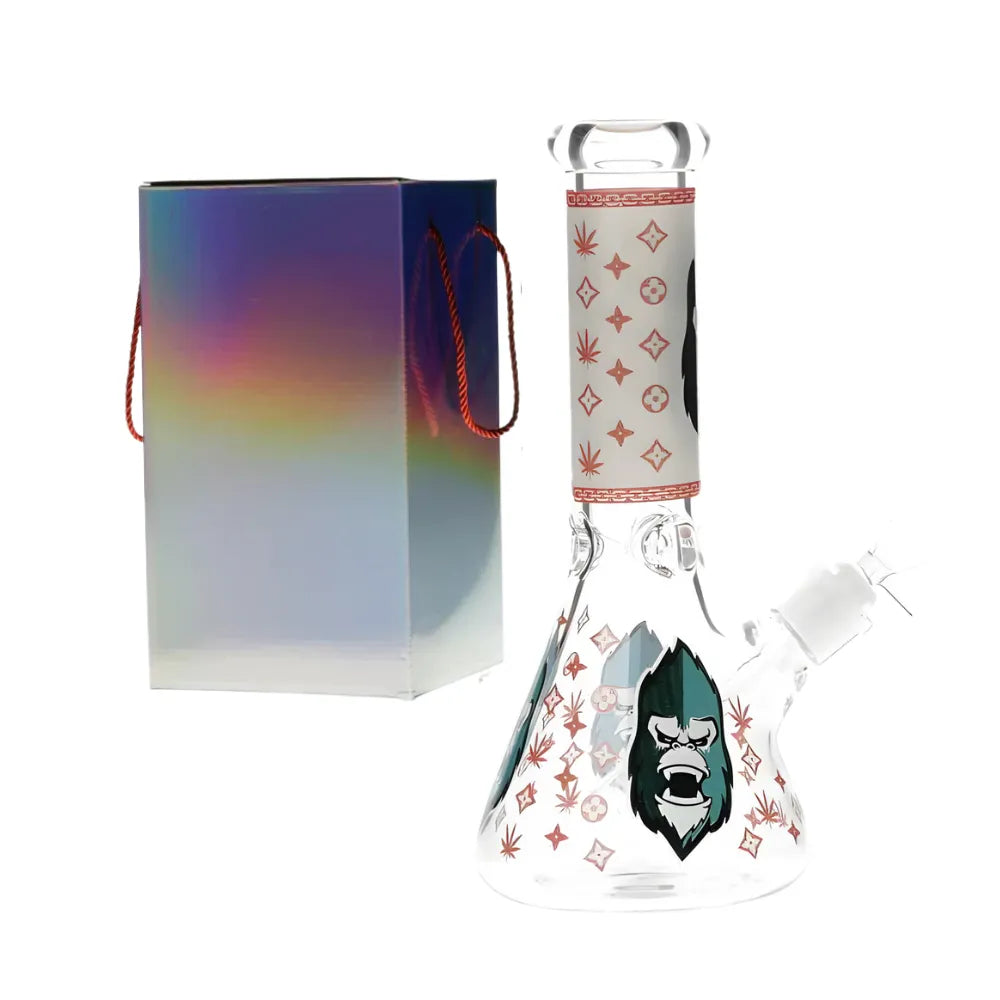 Glass glow in the dark bong with a gorilla design with red accents with colourful packaging on a white background.