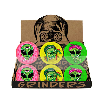Set of alien-themed grinders in a display box with a cartoon face on a white background.