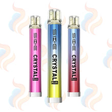 Three SKE Crystal Plus vape devices in pink, blue, and red on a white background with smoke effects.